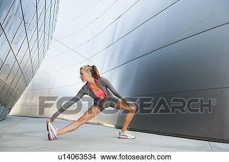Picture - USA, California, Los Angeles, Young woman listening to music on headphones while training. Fotosearch