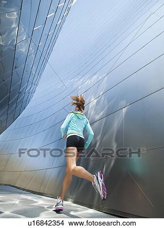 Picture - USA, California, Los Angeles, Young woman jogging in city. Fotosearch