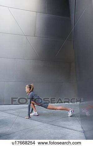 USA, California, Los Angeles, Young woman stretching near modern building View Large Photo Image Picture - USA, California, Los Angeles, Young woman stretching near modern building. Fotosearch