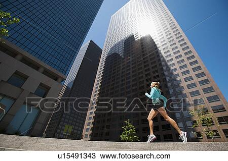 Stock Image - USA, California, Los Angeles, Young woman running in city. Fotosearch