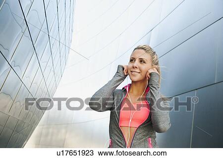 Stock Image - USA, California, Los Angeles, Young woman listening to music on headphones while training. Fotosearch