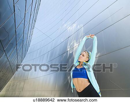 Stock Image - USA, California, Los Angeles, Young woman exercising among office buildings. Fotosearch