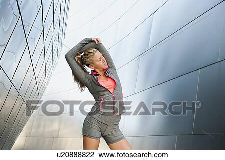 USA, California, Los Angeles, Young woman stretching near modern building View Large Photo Image Stock Image - USA, California, Los Angeles, Young woman stretching near modern building. Fotosearch