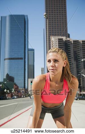Stock Image - USA, California, Los Angeles, Young woman resting after running on city street. Fotosearch