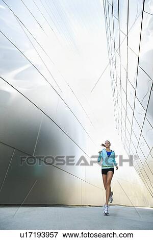 Stock Photo - USA, California, Los Angeles, Young woman jogging in city. Fotosearch