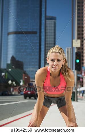 USA, California, Los Angeles, Young woman resting after running on city street View Large Photo Image Stock Photo - USA, California, Los Angeles, Young woman resting after running on city street. Fotosearch