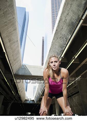 Stock Photography - USA, California, Los Angeles, Young woman resting after running on city street. Fotosearch