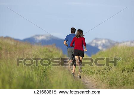 Stock Photography - USA, Montana, Kalispell, Couple jogging in mountainside. Fotosearch