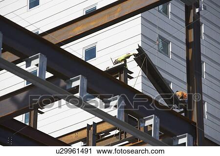 Stock Image - USA, New York, Long Island, New York City, Male workers on construction site. Fotosearch