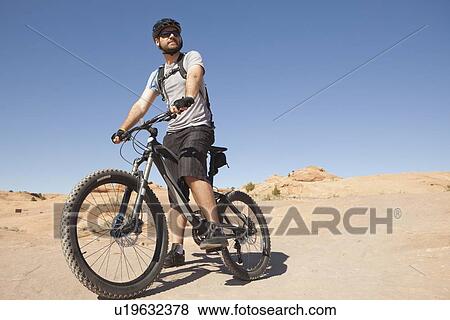 Stock Photo - USA, Utah, Moab, Mid adult man riding mountain bicycle in remote scenery. Fotosearch