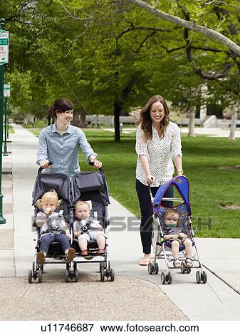 USA, Utah, Salt Lake City, Two young mothers walking with two baby boys (6-11 months) and toddler girl (2-3) in push prams View Large Photo Image Stock Photo - USA, Utah, Salt Lake City, Two young mothers walking with two baby boys (6-11 months) and toddler girl (2-3) in push prams. Fotosearch