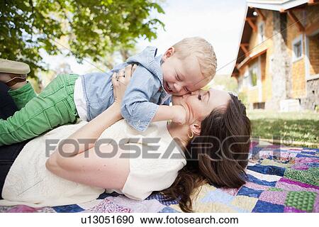 Stock Image - USA, Utah, Salt Lake City, Young mother kissing toddler boy ( 2-3). Fotosearch
