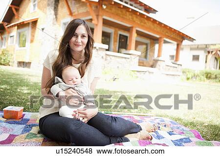 Stock Photo - USA, Utah, Salt Lake City, Young mother with baby boy ( 2-5 months) lying on blanket. Fotosearch