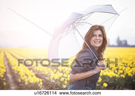 Picture - USA, Washington, Skagit Valley, Woman with umbrella against daffodil field. Fotosearch