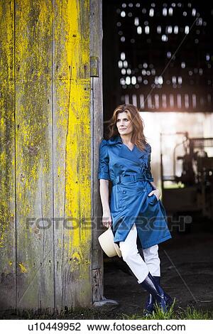 Stock Image - USA, Washington, Skagit Valley, Woman leaning on barn gate. Fotosearch