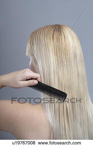 Stock Photo - Woman combing hair, studio shot. Fotosearch