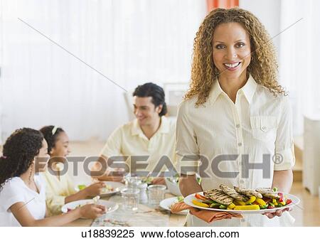 Woman holding dinner plate, with husband and daughters (10-13) in background View Large Photo Image Stock Photography - Woman holding dinner plate, with husband and daughters (10-13) in background. Fotosearch