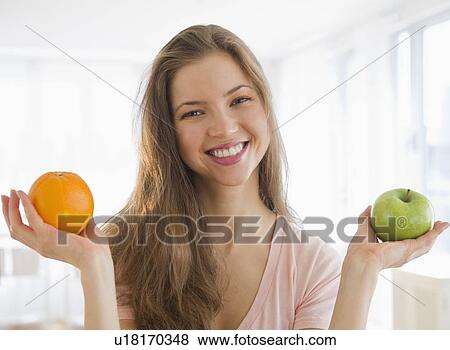 Woman holding orange and apple View Large Photo Image Stock Photo - Woman holding orange and apple. Fotosearch