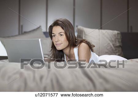 Stock Photo - Woman in bed using laptop. Fotosearch