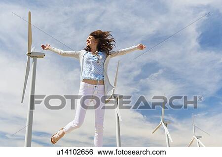 Woman jumping in front of wind turbines View Large Photo Image Stock Photograph - Woman jumping in front of wind turbines. Fotosearch