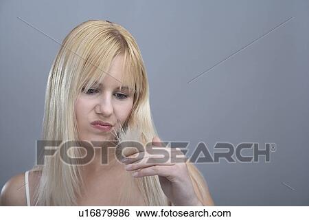 Woman looking disapprovingly at split ends, studio shot View Large Photo Image Stock Photograph - Woman looking disapprovingly at split ends, studio shot. Fotosearch