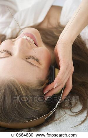 Woman lying on bed and listening to the music View Large Photo Image Stock Image - Woman lying on bed and listening to the music. Fotosearch