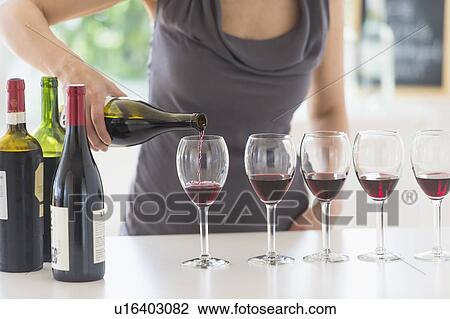 Woman purring red wine into wine glasses View Large Photo Image Stock Image - Woman purring red wine into wine glasses. Fotosearch