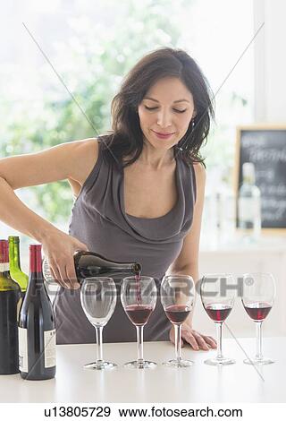 Woman purring red wine into wine glasses View Large Photo Image Stock Photo - Woman purring red wine into wine glasses. Fotosearch