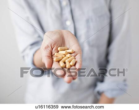 Stock Photo - Woman showing handful of pills. Fotosearch