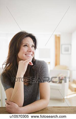 Stock Photography - Woman sitting at table and smiling. Fotosearch