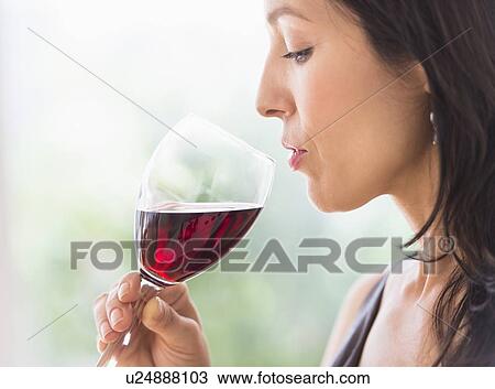 Stock Image - Woman tasting red wine. Fotosearch