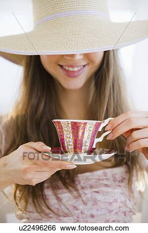 Woman wearing sun hat drinking tea View Large Photo Image Stock Photograph - Woman wearing sun hat drinking tea. Fotosearch
