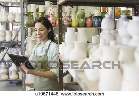 Stock Photo - Woman with digital tablet in pottery warehouse. Fotosearch