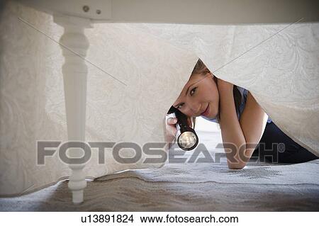 Woman with flashlight looking under bed View Large Photo Image Picture - Woman with flashlight looking under bed. Fotosearch