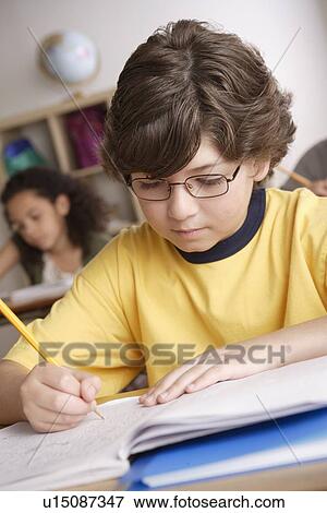 Writing boy (10-11) with girl (10-11) in background View Large Photo Image Stock Photo - Writing boy (10-11) with girl (10-11) in background. Fotosearch