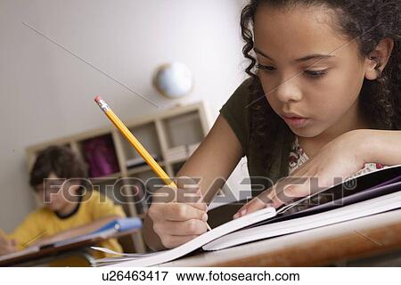 Stock Photo - Writing girl (10-11) with boy (10-11) in background. Fotosearch