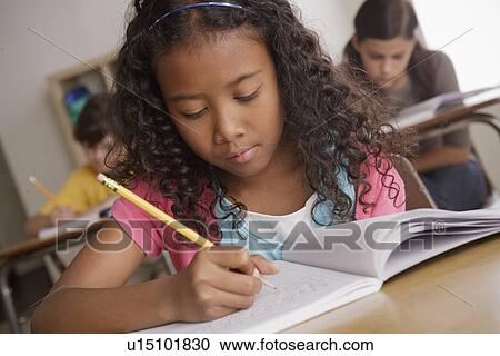 Stock Image - Writing girl (10-11) with girl (12-13) and boy (10-11) in background. Fotosearch