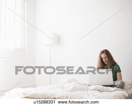 Young attractive woman using laptop in bed View Large Photo Image Stock Image - Young attractive woman using laptop in bed. Fotosearch