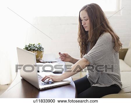 Young attractive woman using laptop while sitting on sofa View Large Photo Image Stock Image - Young attractive woman using laptop while sitting on sofa. Fotosearch
