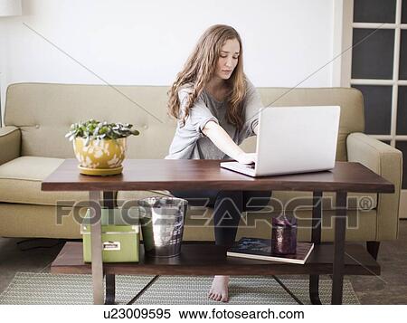Young attractive woman using laptop while sitting on sofa View Large Photo Image Stock Photography - Young attractive woman using laptop while sitting on sofa. Fotosearch