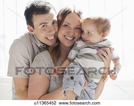 Stock Image - Young couple embracing baby boy (6-11 months) . Fotosearch