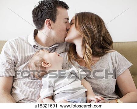Young couple kissing with baby boy (6-11 months) on their lap View Large Photo Image Stock Image - Young couple kissing with baby boy (6-11 months) on their lap. Fotosearch