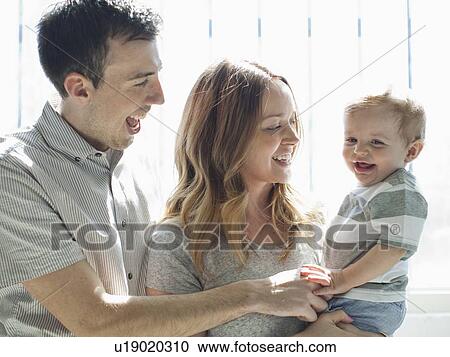 Stock Image - Young couple playing with baby boy (6-11 months) . Fotosearch