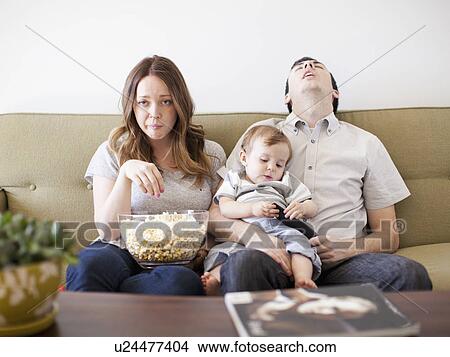 Young couple with baby boy (6-11 months) watching TV View Large Photo Image Picture - Young couple with baby boy (6-11 months) watching TV. Fotosearch