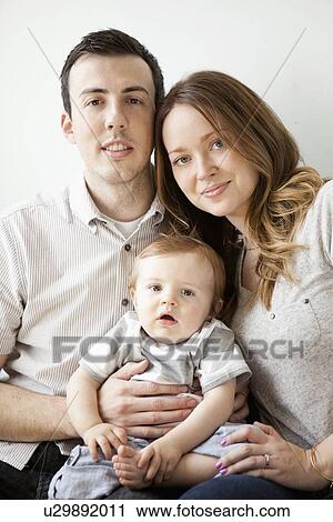 Young couple with baby boy (6-11 months) sitting on sofa View Large Photo Image Stock Image - Young couple with baby boy (6-11 months) sitting on sofa. Fotosearch