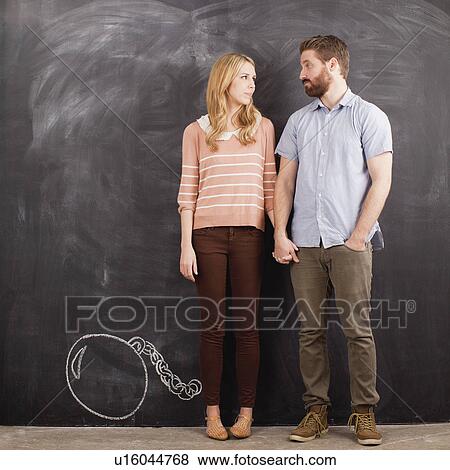 Young couple with blackboard in background, studio shot View Large Photo Image Stock Photo - Young couple with blackboard in background, studio shot. Fotosearch