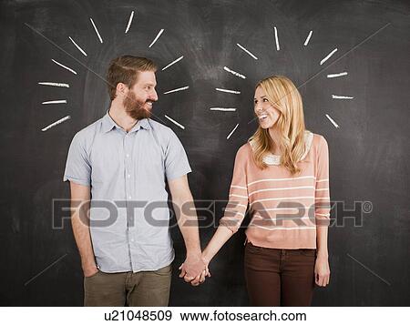 Young couple with blackboard in background, studio shot View Large Photo Image Stock Photo - Young couple with blackboard in background, studio shot. Fotosearch
