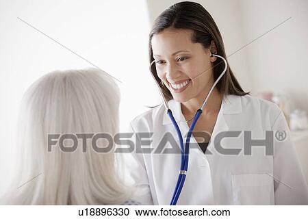 Young doctor examining senior patient View Large Photo Image Stock Image - Young doctor examining senior patient. Fotosearch