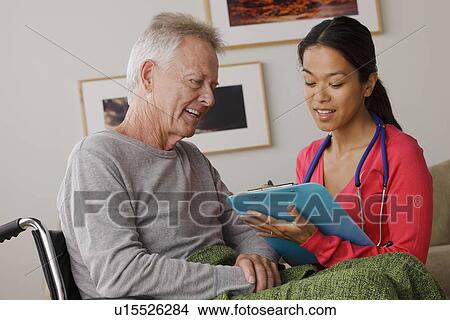 Picture - Young female nurse taking care of senior man. Fotosearch