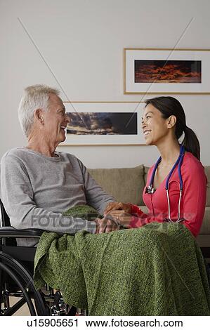 Stock Image - Young female nurse taking care of senior man. Fotosearch